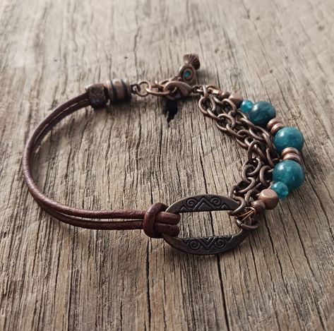 ME-201 Leather & Blue Apatite Copper Multi Strand Mother Earth Collection This mixed media multi-strand boho style bracelet is the perfect for layering. The leather and chains create a beautiful compliment to our stretch strung bead bracelet and leather necklace. The Brown leather enhances the beauty of the tribal copper bead while the sea green Apatite creates a stunning pop of contrast like earth and sea This nature inspired boho bracelet closes with a lobster claw and has a spiral copper and Apatite dangle. It measures 7 1/2" including the clasp. The Blue Apatite gemstone beads add a brilliant pop of color to the copper chain and beads. They also are known to have a metaphysical property to clear confusion, and to clear anger, apathy and confusion.  The spiral has had a lot of different Bead And Leather Bracelet, Diy Boho Bracelets How To Make, Laboradite Jewelry, Leather Jewelry Bracelet, Leather Beaded Bracelet, Leather Bracelet Tutorial, Leather Cord Jewelry, Boho Jewelry Diy, Leather Jewelry Making