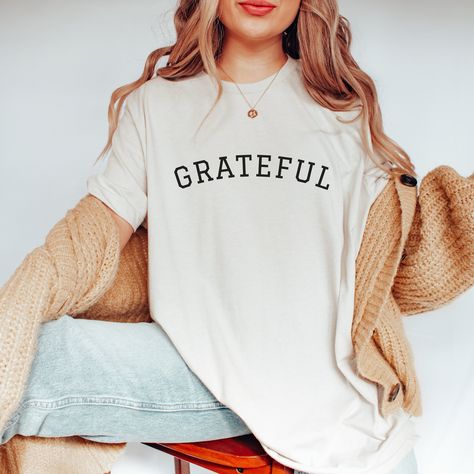 Gratitude is the attitude! Show your gratitude with this simple athletic style T-Shirt for men or women.  Perfect as a gift for mom, gift for dad, Thanksgiving T-Shirt, Christmas Gift, Gift for someone recovering. Grateful T-Shirt, Grateful TShirt, Grateful Tee, Christian Shirt, Women's Grateful Shirt, Inspirational Shirt, Unisex Adult Clothing, Thankful, Blessed.  Black lettering on light colored shirts, white lettering on dark colored shirts. This classic unisex jersey short sleeve tee shirt fits like a well-loved favorite. Soft cotton and quality print make users fall in love with it over and over again. These t-shirts have-ribbed knit collars to bolster shaping. The shoulders have taping for better fit over time. Dual side seams hold the garment's shape for longer. Bella+Canvas manufac Grateful Shirt, Athletic Style, Thanksgiving Shirt, Christian Shirt, Shirt Fits, Inspirational Shirt, Thanksgiving Shirts, Athletic Fashion, Christian Shirts