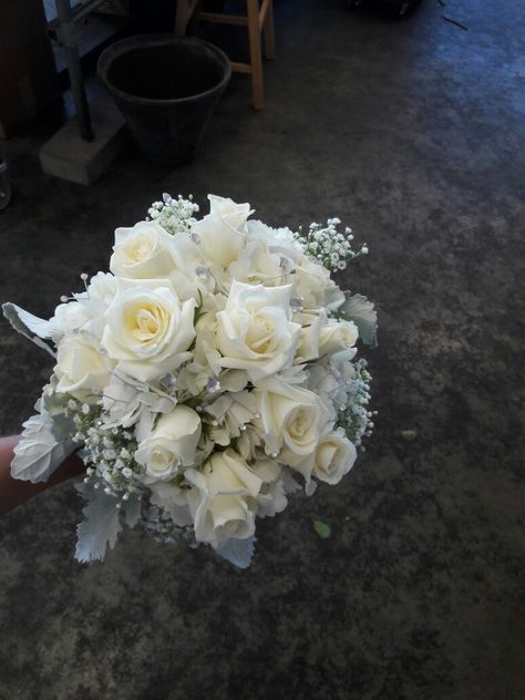 White bridal bouquet using white roses, hydrangea, baby's breath and dusty miller, accented with silver jewels. Made at Oberer's Flowers in Cincinnati. White And Grey Flower Bouquet, Silver Prom Bouquet, Silver Wedding Bouquets, Silver Flower Bouquet, Silver Wedding Gowns, White Wedding Flowers Bouquet, Prom Flowers Bouquet, Silver Bouquet, Hoco 2024