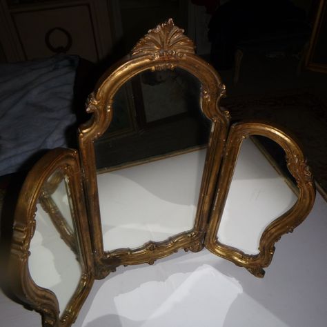 Being offered is this ornate gold toned wooden framed Mirror. Measuring  26 1/2" wide open, 24 1/4" high and  12'closed.. It is very heavy 10+ pounds unpackaged.. It does have some chipping/flaws   thru-out mainly on the sides. The mirror rests on ornate feet and the top is adorned with Acanthus foliage. This is an old used mirror in great vintage condition despite it's age. Thank You for viewing. Mirror Large, Antic Mirror, Vintage Decor Pieces, Antique Vanity Mirror, Large Decorative Mirrors, Room Mirrors, Full Size Mirror In Bedroom, Mirror Vintage, Antquie Mirror