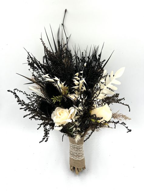 Gothic Wedding Bouquet: Black Flower and White Rose Arrangement Delve into the realm of the romantic and mysterious with our Gothic Wedding Bouquet. This meticulously curated arrangement of black flowers and white roses is the epitome of Gothic elegance, designed for the bride with a penchant for the unconventional. Unique Black Bouquet: The allure of the dark blossoms is undeniable. The rich, black flowers are hand-selected for their velvety petals and deep hue, providing a captivating contrast to the traditional white bridal gown. This unique black bouquet is not only a beautiful accessory but a bold statement of individuality. Elegant White Rose Bridal Accessory: White roses, synonymous with love and purity, are interwoven with the dark blossoms creating a surreal yet elegant display. T Flowers To Go With Black Dress, Gothic Bridesmaid Bouquet, Black And White Boho Wedding, Black And White Flower Bouquet, Dark Wedding Bouquet, Masculine Flowers, Black And White Wedding Bouquet, Black Flowers Bouquet, Black Wedding Bouquet