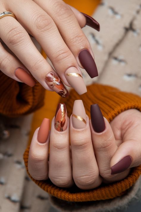 Embrace the beauty of autumn with these stunning coffin-shaped fall nail ideas. Featuring rich hues of burgundy and burnt orange along with delicate gold accents, this nail style captures the essence of the season perfectly. Whether you're dressing up for a pumpkin spice outing or simply showcasing your seasonal spirit, these nails are the ideal statement. Get inspired for your next manicure! Fall Nails Ideas Autumn Burgundy, Orange And Tan Nails, Orange And Burgundy Nails, Fancy Fall Nail Designs, Burgundy Autumn Nails, Fall Bride Nails, Coffin Autumn Nails, Matte Burnt Orange Nails, Coffee Inspired Nails