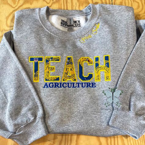 Inspire success with our TEACH Agriculture FFA Personalized Embroidered Crewneck Sweatshirt! Made with pride and precision, this customizable sweatshirt showcases your passion and dedication to the FFA organization. Stay warm and represent your commitment to agriculture education in style. THIS IS A PHYSICAL PRODUCT. CREWNECK IS UNISEX. CREWNECK IS EMBROIDERED. Ffa Jacket Shadow Box Ideas, Ag Teacher Gift Ideas, Ffa Advisor Gifts Ideas, Ag Classroom Decorations, 4h Shirts Design Ideas, Ffa Week Ideas, Ffa Teacher, Ag Teacher Outfits, Reverse Embroidery