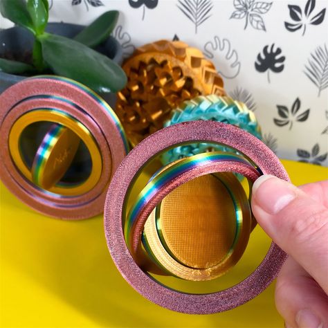 "Need a quieter fidget? We got you covered with this 4-piece gyro coin. These captivating fidget spinners delight restless folks of all ages - great for stocking stuffers, party favors, and giveaways! We love the rainbow with our fast-changing filament for a wide spectrum of color, but we offer a variety of colors for the spinner of your choice.  Grab the default model with a smooth central disc, the winter-themed snowflake, or add a short name or initials to the center for a personalized toy. Make it yours! Gyro spinners measure 3\" (76mm) across.  About our 3D Prints: Our designs are created right here at home. We design and test each item, and then print using the Bambu Labs P1P printer. Due to the nature of 3D printing, finished products may differ slightly in color and finish. Colors Sales Ideas, Snowflake Lights, Fidget Spinners, Frame By Frame Animation, Spinner Toy, Unique Holiday Gifts, Holiday Centerpieces, Winter Themed, Grand Rapids Mi