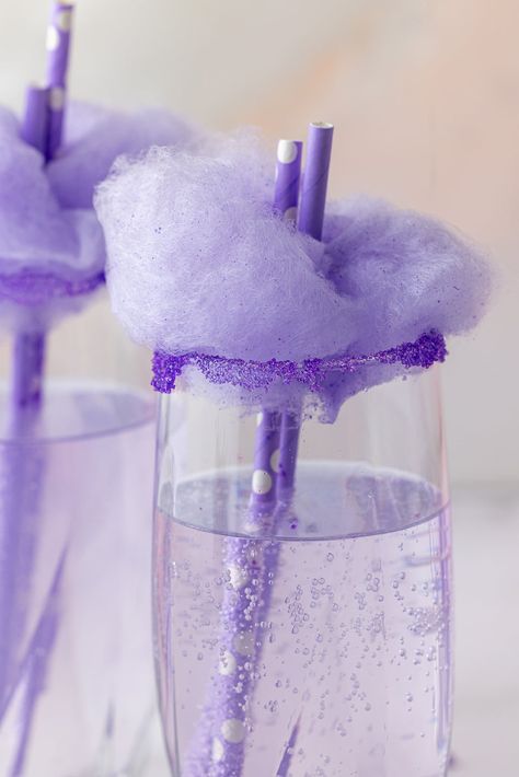 closeup view of purple soda in a glass topped with purple cotton candy, purple colored sugar on the rim of the glasses and purple straws Purple Champagne Drinks, Purple Party Food, Purple Drinks Non Alcoholic, Purple Snacks, Cotton Candy Mixed Drink, Purple Party Foods, Purple Glitter Drink, Cotton Candy Glitter Drink, Purple Cotton Candy Aesthetic