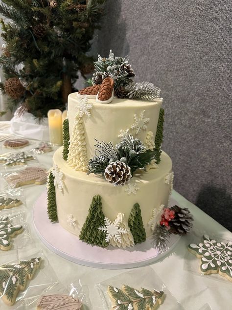 Winter two tier cake with evergreens, pine cones and snowflakes. Perfect for a baby its cold outside shower. Baby It’s Cold Outside Shower Cupcakes, Winter Woodland Cake, It’s Cold Outside Baby Shower Cake, Baby It’s Cold Outside Cake, Winter Forest Baby Shower Theme, Christmas Baby Shower Cake, Winter Baby Shower Cake, Forest Baby Shower Theme, Winter Wonderland Cake