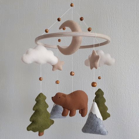 Woodland mobile nursery with bear is an ideal and original baby shower gift that will perfectly decorate the nursery baby girl or boy in the Scandinavian style.Your baby will love this cute bear and will not only enthusiastically consider them, also develop crib mobile teaches him to focus his eyesight. SIZE:the diameter of the ring ~ 22 cm (8,6 inch)full mobile length ~ 37 cm (14,5 inch) MATERIALS:Felt American, KoreanHypoallergenic holofiber fillerWooden ringbaseStrong cotton threadWooden bead Crib Mobile Ideas, Mountain Mobile Nursery, Winter Woodland Nursery, Boy Nursery Forest Theme, Woodland Mobile Nursery, Felt Mobile Baby, Moose Baby Nursery, Cabin Nursery Theme, Baby Boy Nursery Forest