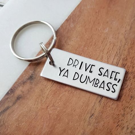 An adorable gift for any dumbass in your life! Perfect for your little brother or sister that just started driving. This keychain is so funny and will surely put a smile on the recipient's face! Item Details: Text on keychain: Drive Safe, Ya Dumbass Color: silverMetal: lightweight aluminumTag Size: 14 gauge, 5/8” x 1.5" Hardware: Stainless steel split ring, stainless steel key ring Options: - Keychain Only (main keychain tag only) - Add Name Charm (main keychain tag, plus round name charm) About this item:Keychains are stamped on 14 gauge aluminum. This is a preferred metal for many metal stampers. Aluminum is a very lightweight metal that will not rust, or tarnish. It is a lightweight metal, so it will not weigh down your key ring. Light scratching is normal with use and wear. Although it Car Gifts For Boyfriend, Car Gift Ideas, Funny Keychains, Funny Photos Ideas, Stocking Stuffers For Boys, Funny Keychain, Teen Driver, Hand Stamped Keychain, Wooden Keychain