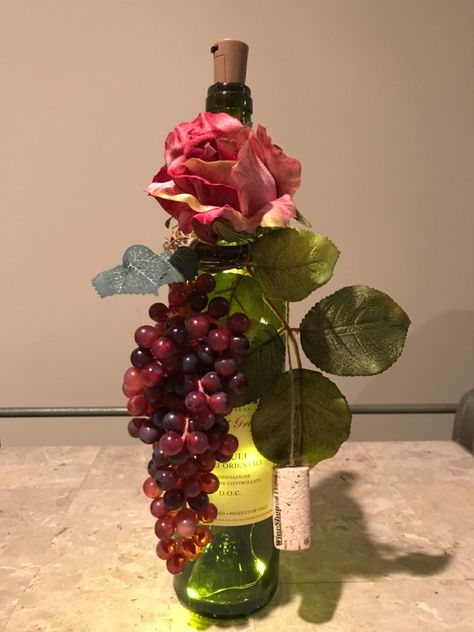 Lighted wine bottle and decorated using a small grape vine wreath, grapes, leaves and a flower with a cork and twine. Bottles Decoration Diy, Grape Kitchen Decor, Wine Bottle Centerpieces, Grapes Leaves, Bottle Decoration, Vine Wreath, Bottle Diy, Craft Things, Wine Bottle Diy