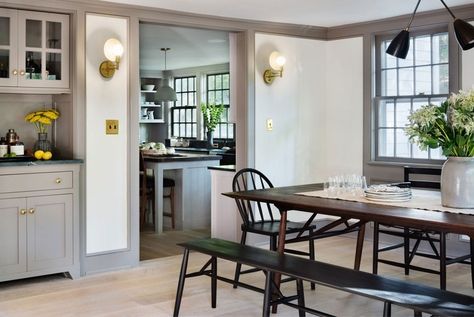 The warm gray paint that cloaks the trim on this farmhouse kitchen by Hendricks Churchill helps keep the even darker accents, like brass and black, from feeling stark against white walls | archdigest.com Black Dining Room Sets, Baseboard Styles, Millwork Wall, Farrow & Ball, Farmhouse Renovation, Gray Trim, Farmhouse Remodel, Weekend House, Small Farmhouse