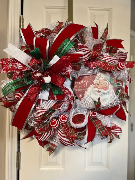 Want the perfect Santa wreath this Holiday Season?  You cannot go wrong with this wreath.  It has a picture of Santa stating "Believe in thew Magic of Christmas" It has white deco mesh and a red and green plaid deco mesh.  It has different ribbons in red & white.  In the bottom right corner is a glittered Santa boot.  It has red and white balls scattered all over.  The tartan plaid ribbon matches the deco mesh.  It has a big Christmas bow in the top left corner with red and white ornaments in the center.  The pictures listed show a variance of colors but the true color is Christmas red.  You will be happy to have this addition to your Christmas decorations. MATERIALS: All Wreaths are designed and created by myself and made with high quality artificial florals, greenery, ribbon & deco mesh Santa Deco Mesh Wreath, Christmas Deco Mesh Wreaths Ideas, Santa Wreaths For Front Door, Santa Wreaths Diy, Mesh Christmas Wreaths Diy, Big Christmas Bow, Santa Wreath Diy, Red And White Ornaments, Santa Claus Wreath