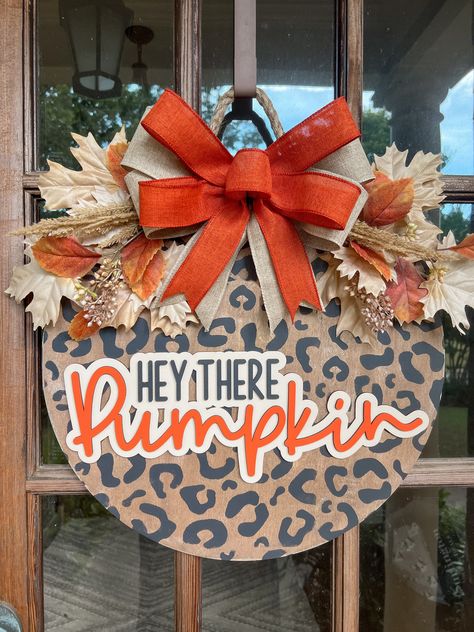 The adorable cheetah print door hanger is the perfect addition to your Fall decorations! The door sign measures 18 inches in diameter and is 1/2 inch thick. The 3D lettering is cut from 1/8 inch wood. The bow and leaves are attached with staples, and the sign is finished with a decorative rope for hanging.  Please messsage me with any questions or special requests. Thank you for visit my shop! Stitch Door Hanger, Checkered Door Hanger, Sunflower Round Door Hanger, Wooden Fall Door Hangers, Fall Wood Door Hangers, Fall Door Hanger Ideas, Diy Halloween Door Hanger, Fall Diy Crafts For Adults, Fall Door Hangers Wooden