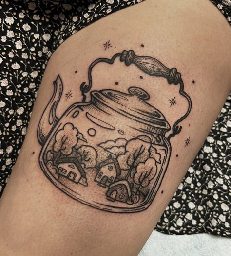 Thigh tattoo of a tea kettle with tiny houses and trees inside done in black line and dot style. Tea Kettle Tattoo, Kettle Tattoo, White Tea Kettle, Cottagecore Tattoo, Teapot Tattoo, Cottagecore Tea, Nature Tattoo Ideas, Tea Tattoo, Teacup Tattoo