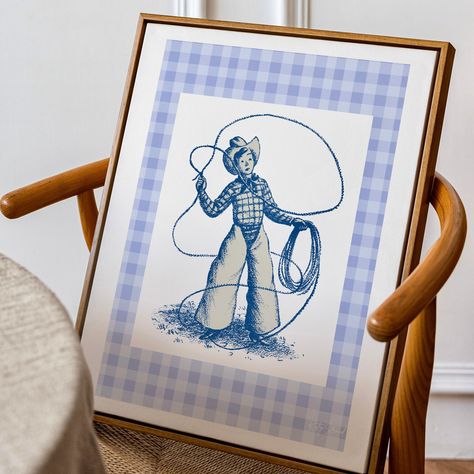 Baby blue vintage western art print. Designed by British artist and designer Kitty Strand - Studio Kitti.  Add a touch of western flare to your decor with the playful vintage style cowboy art print! The epitome of playfulness, whimsy & vintage design. A rope twirling young cowboy is framed by a soft border of fabric inspired gingham. Ideal for playrooms, nursery or as a gift for the young at heart!  Perfect for gallery walls, adding a spark of fun to home spaces, dorm rooms or as a playful uniqu Vintage Cowboy Art, Cowboy Nursery, Western Wall Decor, Cowgirl Gifts, Western Babies, Western Wall, Luxury Printing, Cowboy Art, Vintage Cowboy