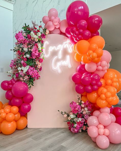 Celebrate your graduating princess with our stunning orange and pink balloon setup, complete with beautiful florals, a custom neon sign, and a chic backdrop! 🎈🌸✨ The perfect setting for an unforgettable graduation day. ✨🥳 Pink And Orange Balloon Backdrop, Pink Orange Backdrop, Balloon Floral Backdrop, Floral Balloon Backdrop, Pink And Orange Balloons, Pink And Orange Backdrop, Orange And Pink Grad Party, Pink And Orange Decorations, Pink And Orange Balloon Garland