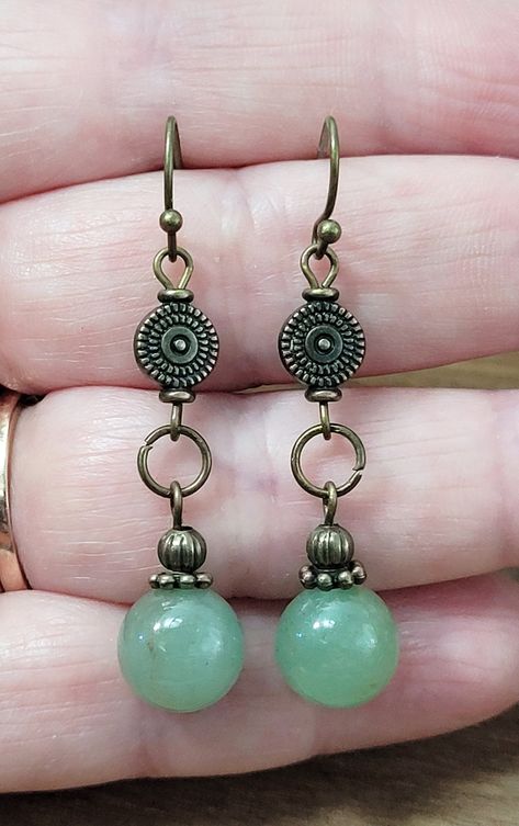 Embrace the allure of nature with these Aventurine Stone Dangle Earrings, beautifully handcrafted to capture the essence of bohemian charm. These exquisite earrings feature genuine jade green aventurine stones, each unique in its rustic, earthy hue, nestled in an elegant bronze setting. Perfect for adding a touch of organic beauty to any outfit, these lightweight, comfortable earrings dangle gracefully, catching the light with every movement. Whether you're dressing up for a special occasion or simply embracing your everyday boho style, these earrings make a thoughtful, handmade gift for nature lovers and free spirits alike. Discover the authentic beauty of bohemian bronze jewelry today!These gorgeous rustic antiqued bronze and aventurine stone boho style earrings with beautiful antiqued b Seed Jewelry Natural, Bronze Dangle Earrings, Charm Earrings Diy, Unique Diy Earrings Ideas, Diy Boho Jewelry, Handmade Earrings Ideas, Boho Earrings Diy, Whimsical Earrings, Comfortable Earrings