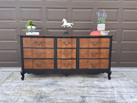 This beautifully refinished French Provincial dresser combines classic elegance with modern flair. The piece features a sophisticated two-tone finish, with the body and trim painted in a rich, velvety black, perfectly complementing the natural wood tones of the drawer fronts and top surface. The original hardware has been meticulously restored, adding a touch of vintage charm. With its elegant curves and solid craftsmanship, this dresser is not only a stunning focal point but also offers ample storage with its six spacious drawers. It's perfect for adding a touch of timeless style to any bedroom, entryway, or living space. Dimensions: 65" L x 32" T x 19" D Condition: Excellent vintage condition, fully restored Materials: Solid wood, metal hardware Finish: Hand-painted black with natural wo Black French Dresser, Wood Dresser Painted Drawers, Painted Dresser Stained Drawers, Black Dresser Wood Top, Two Tone Wood Furniture, Black And Natural Wood Dresser, Brown Painted Furniture, Two Tone Dresser Painted, Black And Wood Furniture