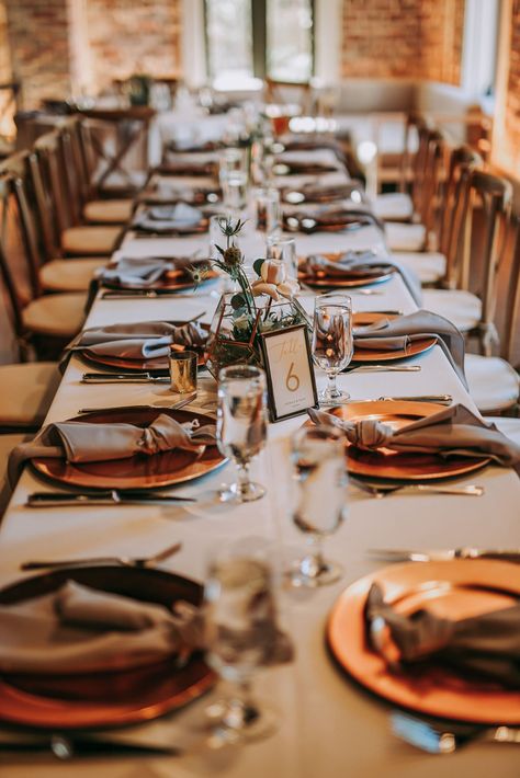 Long Feasting Tables with White Linens and Copper Charger Plates with Taupe Napkins for Wedding Reception | Perfecting the Plan Copper Charger Plates Table Settings, Copper Table Setting, Napkins For Wedding Reception, Copper Charger Plates, Green Table Settings, Disposable Wedding Plates, Unique Wedding Table Decorations, Charger Plates Wedding, Napkins For Wedding