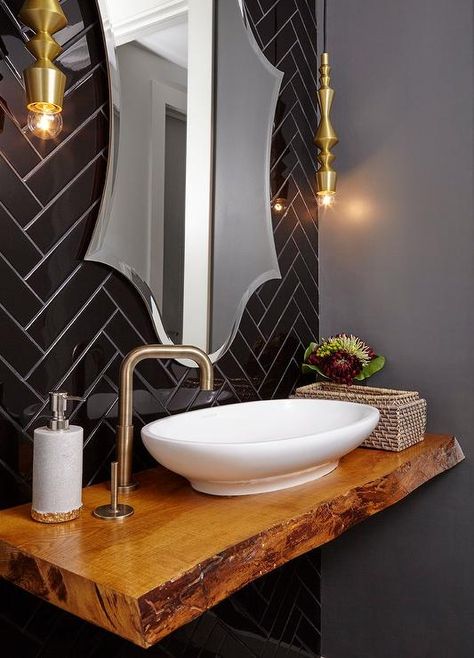 Chic contemporary powder room showcases a stunning live edge floating vanity finished with an oval vessel sink with a brass faucet fixed to the side of the sink beneath a beveled vanity mirror lit by brass light pendants mounted on black herringbone wall tiles. Herringbone Wall Tile, Black Powder Room, Contemporary Powder Room, Diy Vanity Mirror, Floating Sink, Sink Decor, Bad Inspiration, Diy Vanity, Powder Rooms