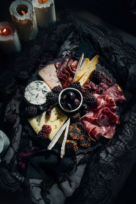 Dark-themed charcuterie board with assorted cheeses, cured meats, blackberries, and olives, placed on a vintage black lace cloth with candlelight for dramatic effect. Charcuterie Lazy Susan, Moody Grazing Table, Food Bar Aesthetic, Dark Cheese Board, Witch Theme Charcuterie Board, Halloween Wine And Cheese Party, Charcuterie Board Dark Aesthetic, Moody Tablescape Dinner Party, Spooky Food Board