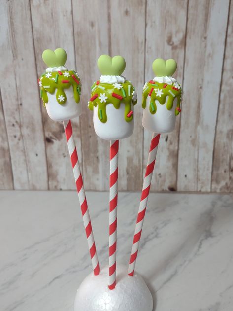 "Faux marshmallow GRINCH-themed lollipops. Green chocolate dipped and whipped topping with candy sprinkles.  Decorate your Grinchmas tiered tray or holiday decor!  This listing is for ONE Grinch Pop. FREE Gift wrapping and note from sender option.   Intended for display, not to eat! Measures approximately 1 1/4\" wide and 10\" tall. Carefully packaged, padded, and shipped with care.   Willing to bundle, message me with any questions!" Christmas Chocolate Lollipops, Diy Marshmallow Ornaments, Grinch Dessert Table, Grinch Lollipops, Grinch Marshmallow, Grinch Truffles, Grinch Christmas Decorations Diy, Grinchmas Decorations Diy, Marshmallow Pops Christmas