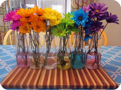 I love doing this with flowers!  You put food coloring in the water and the stem of the flower soaks it up and changes the color of the flower.  ~T Colorful Flower Centerpieces For Party, Flower Power Centerpieces, Rainbow Table Decorations, Rainbow Flower Arrangement, Color Party Ideas, Color Party Decorations, Color Party Ideas For Adults, Flowers Rainbow, Flower Rainbow