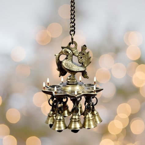 This hanging Diya is designed by Rural artisans from Rajasthan (India). This Wall Decor Diya has been given a peacock design, There are also bells attached which makes it more beautiful. You can use this hanging Diya (Candle) to decorate the temple of your home and wall. It will give a more Holy and beautiful look to your temple. We hope this Brass Candle will make your home more beautiful and glowing Diya Candle, Hanging Diya, Diya Lamp, Diwali Decoration Items, Handmade Lamp, Lamp Hanging, Lantern Candle Decor, Brass Door Handles, Brass Bell