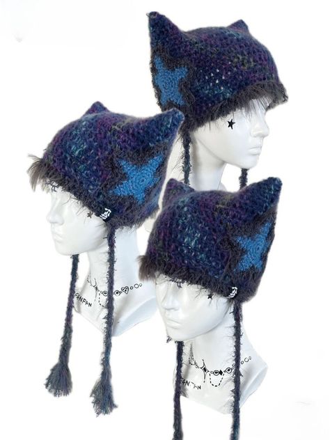 Featuring adorable cat ear shapes adorned with star motifs, this beanie is perfect for keeping you snug and on-trend. Complete with two long tails for added flair, it's the perfect accessory to elevate your winter wardrobe. Embrace the magic of the season with this enchanting addition to your wardrobe, where every wear promises a delightful touch of playful elegance. Hand knit over the course of 4 hours. Polyester & 10% Wool Washing Instructions:Can be washed in low-temperature water and ironed Blue Cat Ears Headband, Cute Winter Accessories, Crochet Star Clothes, Alt Crochet Ideas, Cool Crochet Hats, Crochet Star Hat, Cat Crochet Beanie, Crochet Winter Clothes, Cat Ears Beanie