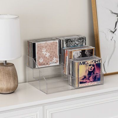 This trendy 3-tier clear acrylic CD storage rack is expertly perfect for showcasing your media collection. With 3 cascading tiers and six compartments, it can elegantly hold up to 36 compact discs, DVDs, or video game discs. Its sleekly designed structure complements any décor, and the 4mm thick acrylic ensures exceptional clarity for quick viewing. Ideally suited for tabletops, desktops, shelves, or inside cabinets, this compact media organizer keeps your collection neatly accessible. Especiall Cd Player Set Up, Cd Display Ideas, Cds Storage, Cd Storage Ideas, Cd Organizer, Cd Stand, Cd Display, Cd Rack, Cd Holder