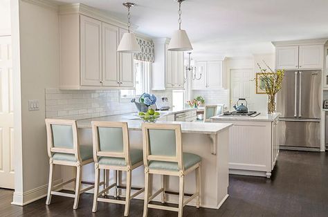 A pair of white pleated pendant lights hang over a kitchen peninsula lined with… Kitchen With Peninsula, Peninsula Kitchen, Black Kitchen Countertops, Kitchen Peninsula, White Kitchen Decor, Leather Counter Stools, Decorating Shelves, Kitchen Island Design, Kitchen Design Decor