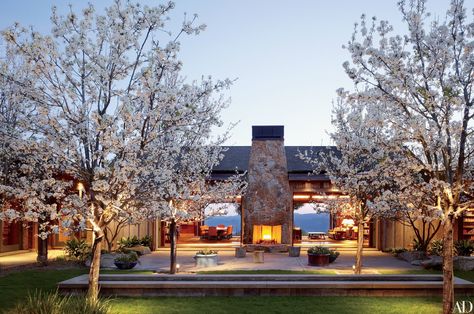 A fireplace anchors a courtyard off the great room of Dana Johnson and Mark Nelson’s 10,000-square-foot residence. They commissioned architect Howard J. Backen to create the house and a winery on the 300-acre property in Napa Valley. Mark W. Bowers was the landscape architect. Rustic Home Exterior, Country Interior Design, Outdoor Fireplace Designs, Modern Country Style, Country House Design, Country House Interior, Wine House, Country Interior, Wine Country California