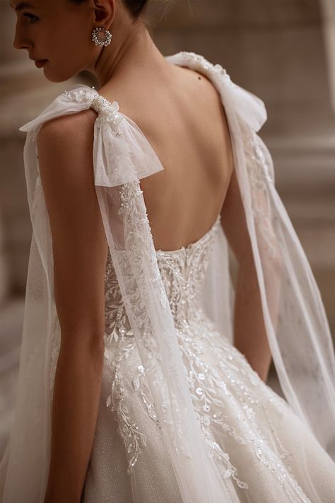 This sleeveless wedding dress features giant sheer fabric bows that rest gracefully on the shoulders. The V-neck bodice is adorned with beautiful floral lace patterns that flow over the waist and down the hips, creating a romantic and intricate design. The glistening chiffon skirt, layered beautifully, flows into a lovely train, adding a sense of grace and sophistication to the overall ensemble. This gown is the perfect choice for a bride seeking a contemporary yet timeless look for her special day. Petite Wedding Dress, Bow Wedding Dress, Sheer Wedding Dress, Pretty Wedding Dresses, Floral Wedding Dress, Wedding Dresses With Straps, Sleeve Wedding Dress, Fabric Bows, Tulle Wedding Dress