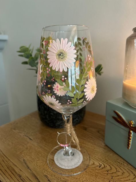 Square style wine glass, hand painted with blush pink daisies and foliage, and finished with a complimentary glass charm. These glasses are suitable for hand washing in warm soapy water, please do not soak, scrub or put in a dishwasher, as this will affect the longevity of your glass Drawing On Wine Glasses, Posca Glass Art, Painted Glass Mugs, Wine Painting Glasses Ideas, Paint On Glass Ideas, Diy Wine Glass Painting Ideas, Painting On Glasses, Glass Mug Painting Ideas, Wine Glass Art Paintings