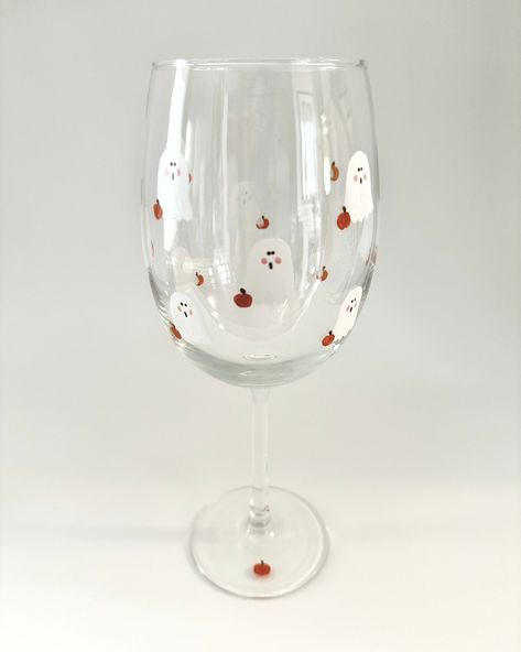 This cute Ghost wine glass has a small pumpkin and is a Halloween gift ready to give as a hostess or birthday gift!  There are 12 white ghosts and 12 little orange pumpkins that are hand painted on each glass.  Fall decor with a Minimalist design.   The glass is 9 inches tall and holds 19 oz.   I use high quality enamel glass paint.  Double painted and heat cured. Hand washing is recommended for years of beauty.   Gift box included with a hand written notecard. Ghost Wine Glass Painting, Glass Painting Designs Halloween, Halloween Diy Wine Glasses, Pumpkin Painted Wine Glasses, Fall Painted Wine Glasses Diy, Painting Glassware Diy, Halloween Glasses Diy, Halloween Glass Painting Ideas, Halloween Wine Glasses Diy Painted