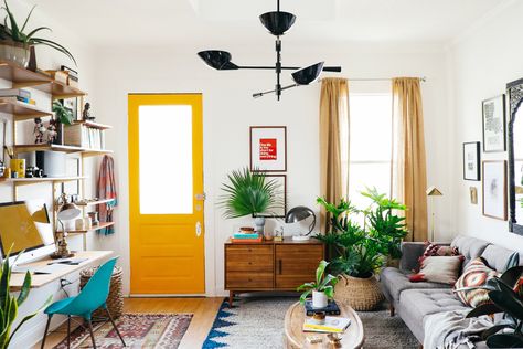 This is my 100 sq.ft. living room makeover I worked on for West Elm. Check  out their blog for more tips! It's a shotgun style home. They're very  popular in New Orleans and dates back to the early 1800s. They're basically  a long and narrow, rectangular house. Ours had the living room in the  front, then kitchen, followed by the dining room, bedroom, and with a  bathroom in the back. The idea is that if you fire a gun at the house, it  would go through each room. A little scary sounding.  I ... Rooms With Plants, Reka Bentuk Ruang Tamu, Living Pequeños, Hiasan Dalaman Rumah, Reka Bentuk Dalaman, Lots Of Plants, Yellow Door, Small Space Design, Bohol