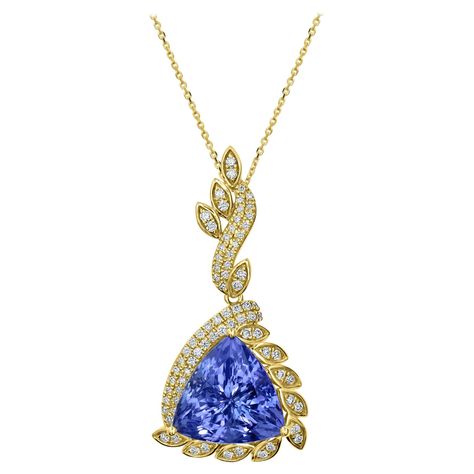 This 10.55 carat Tanzanite pendant with 0.53 total carats of diamonds set in 18K yellow gold is a truly remarkable piece of jewelry. The tanzanite gemstone is a stunning shade of blue-violet that is both striking and elegant. It is perfectly complemented by the yellow gold setting, which adds warmth and richness to the piece. The tanzanite is surrounded by 0.53 carats of diamonds, which are set in a unique halo around the gemstone. One third of the Tanzanite is covered in a simple double halo, w Tanzanite Pendant, Pendant Making, Tanzanite Gemstone, Double Halo, Yellow Gold Setting, Diamond Flower, Blue Violet, Diamond Pendant, Timeless Pieces