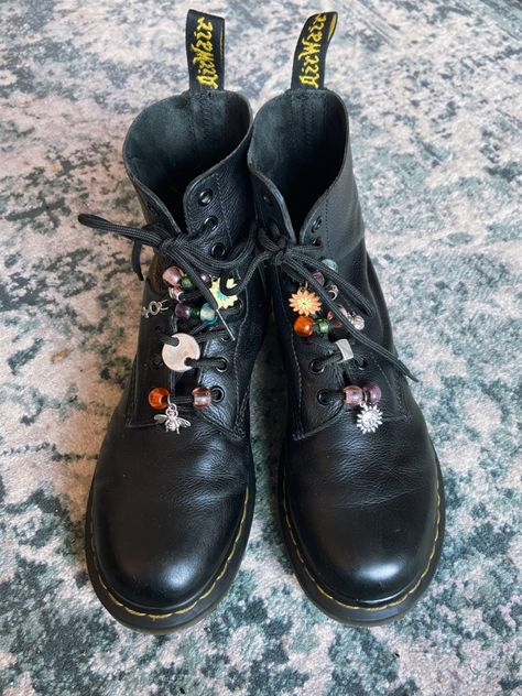 A pair of black doc martens boots with different beads and charms on the laces. Boots Diy, Moda Hippie, Mode Shoes, Beaded Shoes, Witchy Fashion, Looks Black, Moda Vintage, Shoe Charms, Doc Martens