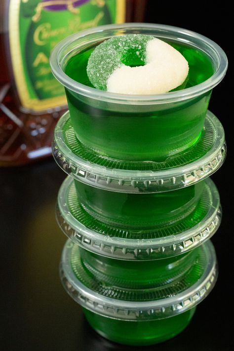 Four 2oz portion containers filled with Crown Apple jello shots are stacked on top of one another in front of a bottle of Crown Apple. Fairy Jello Shots, Green Apple Fireball Jello Shots, Apple Whiskey Jello Shots, Crown Jello Shots Recipe, Apple Jello Shots Recipes, Green Halloween Jello Shots, Sonic Green Apple Jello Shots, Crown Royal Apple Jello Shots, Jello Shots For Halloween Party