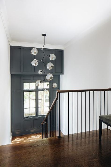 Staircase landing features an accent wall with black paint and wainscoting. Landing Feature Wall, Feature Wall Stairwell, Stair Landing Accent Wall Ideas, Feature Wall On Stairs, Feature Staircase Wall, Stairway Feature Wall, Staircase Wall Paint, Feature Wall Staircase, Staircase Feature Wall