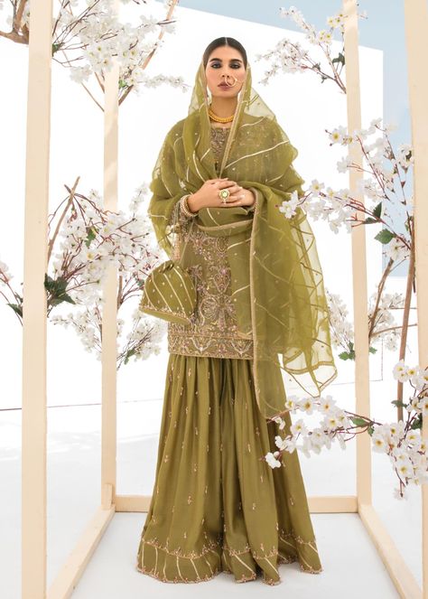 Include: Shirt Dupatta Gharara Pants Fabric: Shirt: Korean Silk Dupatta: Organza Gharara Pants: Korean Silk Color: Olive Description: Mahjabeen features the richness of deep olive green color for this traditional mehndi bride look, curated on Korean raw silk. The short shirt silhouette is astonishingly embellished with timeless gotta, dabka, naqshi, and sitara, adding accent color of pinks. This heavenly silhouette is paired with Korean base gharara, with beautiful hand embellished details on th Mehndi Bride Look, Party Dress Indian, Organza Gharara, Kanwal Malik, Gharara Pants, Traditional Mehndi, Mehndi Bride, Mehndi Outfit, Embroidery Clothes