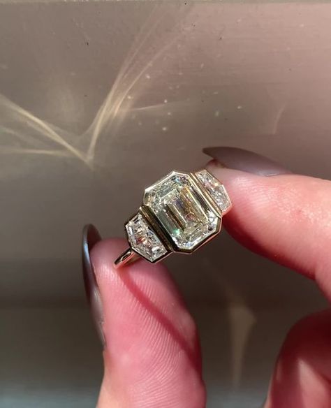 Frank Darling Custom Rings on Instagram: "If there's one thing we love most about bezel-set emerald engagement rings, it's the way the bezels hug the cut corners of your stunning center diamond 😍⁠ ⁠ This emerald diamond also has a slightly chubbier ratio, maximizing its compact sparkle.⁠ ⁠ The Ring:⁠ • 2.7ct Emerald⁠ • I color, VS1⁠ • 9.36 x 6.70 x 4.42 mm⁠ • 14k YG⁠ ⁠ Mark your calendars, darlings! The last day for Thanksgiving proposal orders is November 1st 💍🍁⁠ ⁠ ••⁠ ⁠ #customjewelry #besp Taylor Hill Engagement Ring, Unique Chic Engagement Rings, Emerald Engagement Ring Bezel Set, Bezel Set Three Stone Ring, Three Stone Bezel Ring, Three Stone Bezel Engagement Rings, Frank Darling Engagement Ring, Chunky Engagement Rings Unique, Thanksgiving Proposal