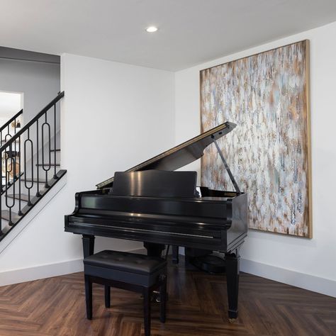 This Baby Grand Piano stands in the corner of the room, accompanied by oversized artwork giving this space a timeless luxury appeal. The dark wood floors add warmth back into the space. Notice how much a simple piece of art can transform the space! #westchesterohio #cincinnatidesign #artanddesign #modernartlovers Piano Corner, Piano Room Design, Grand Piano Living Room, Grand Piano Room, Piano Living Rooms, Oversized Artwork, Baby Grand Piano, Baby Grand Pianos, Piano Room