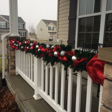 Garland on the front porch. Christmas Porch Banister Decorations, Garland On Front Porch Pillars, Porch Railing Christmas Decorations, Outdoor Banister Christmas Decor, Patio Decorating Ideas Christmas, Balcony Ideas Christmas, Outdoor Christmas Balcony Ideas, Apartment Outdoor Christmas Decor, Garland On Fence Christmas