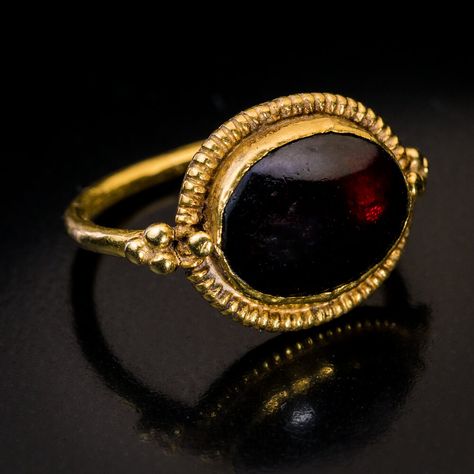 Ancient Byzantine Cabochon Garnet High Karat Gold Ring. This early Byzantine ring, circa 5th-6th centuries CE, is finely crafted in 21 karat gold. The ring features an oval cabochon cut garnet of a deep red color set in a ribbed bezel and flanked at the shoulders by gold beads. Byzantine Fashion History, Ancient Rings Jewelry, Byzantine Jewelry Ancient, Historical Rings, Ancient Rings, Antique Gold Ring, Byzantine Ring, Ancient Roman Jewelry, Byzantine Gold