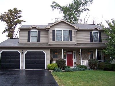 A while ago, I had mentioned that we wanted to eventually redo the outside of our house. Read about it here . Just a reminder of what our house looked like last week: Not bad, just not “us”! We hadn’t planned on doing anything just yet because of several factors, the biggest factor being money … Red Door House, Black Garage Doors, Front Of A House, Garage Door Colors, Tan House, Red Doors, Red Front Door, Black Shutters, House Shutters