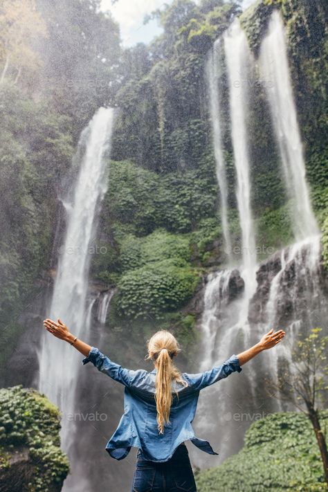 Excited woman standing by waterfall by jacoblund. Rear view of woman standing in front of water fall with her hands raised. Female tourist with her arms outstretched l... Waterfall Pictures, Waterfall Photo, Pose Fotografi, Water Fall, The Tourist, Nature Sounds, Group Travel, Beautiful Waterfalls, Woman Standing