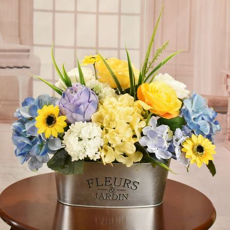 Bring your space to life with such vibrant pops of color all throughout this assorted mixture of florals. Including the colors Yellow, Blue, White, and Greens with grasses and leafs filled throughout. This pop of color arrangements home is in a chic farm galvanized planter. Assorted Bouquet, Pale Blue Hydrangea, Wheat Centerpieces, Artificial Silk Flower Arrangements, Silk Floral Centerpiece, Dried Flowers Crafts, Greenery Wall Decor, Calla Lily Flowers, Silk Arrangements