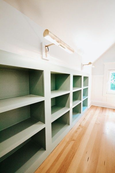 custom built-in bookshelves, bookshelf lights, attic bedroom nook, reading nook, window seat, custom built-ins Attic Renovation Playroom, Built In Shelves Knee Wall, Playroom Sloped Ceiling, Modernize Victorian Home, Attic Library Sloped Ceiling, Office Attic Ideas, Attic Room Storage Ideas, Attic Cabinets, Attic Shelving