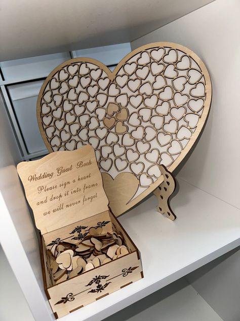 Elevate your wedding day with the most exquisite Heart-Shaped Wedding Guest Book that's bound to leave a lasting impression. This stunning guest book will captivate your guests and create cherished memories as they sign individual hearts and place them within the accompanying frame. Our heart-shaped guest book is more than just a registry; it's a beautiful keepsake designed to commemorate the loved ones who shared in your special day, making it truly unforgettable. Here's what you'll receive, just as showcased in our photographs: - Heart-Shaped Guest Book with an Elegant Wooden Box - A Stand to Display Your Guest Book - Wooden Hearts for Up to 90 Beloved Guests This product is shipped from the UK by ourselves, a small family owned business named Perfect Simplicity. We are delighted to offe Wood Laser Engraving Machine, Book Wedding Decor, Wooden Heart Guest Book, Guest Book Wood, Rustic Guest Book, Wedding Decor Rustic, Elegant Wedding Themes, Wooden Guest Book, Laser Cut Wood Crafts