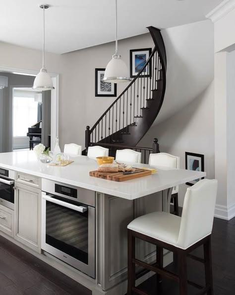 Taupe center kitchen island with an oven and microwave topped with a white quartz counter slab under a set of frosted and chrome pendant lights. Kitchen Island With Cooktop, Circular Staircase, Island With Stove, Kitchen Island With Stove, Custom Island, Taupe Kitchen, Kitchen Island With Sink, Kitchen Island Cabinets, Unique Kitchen Design